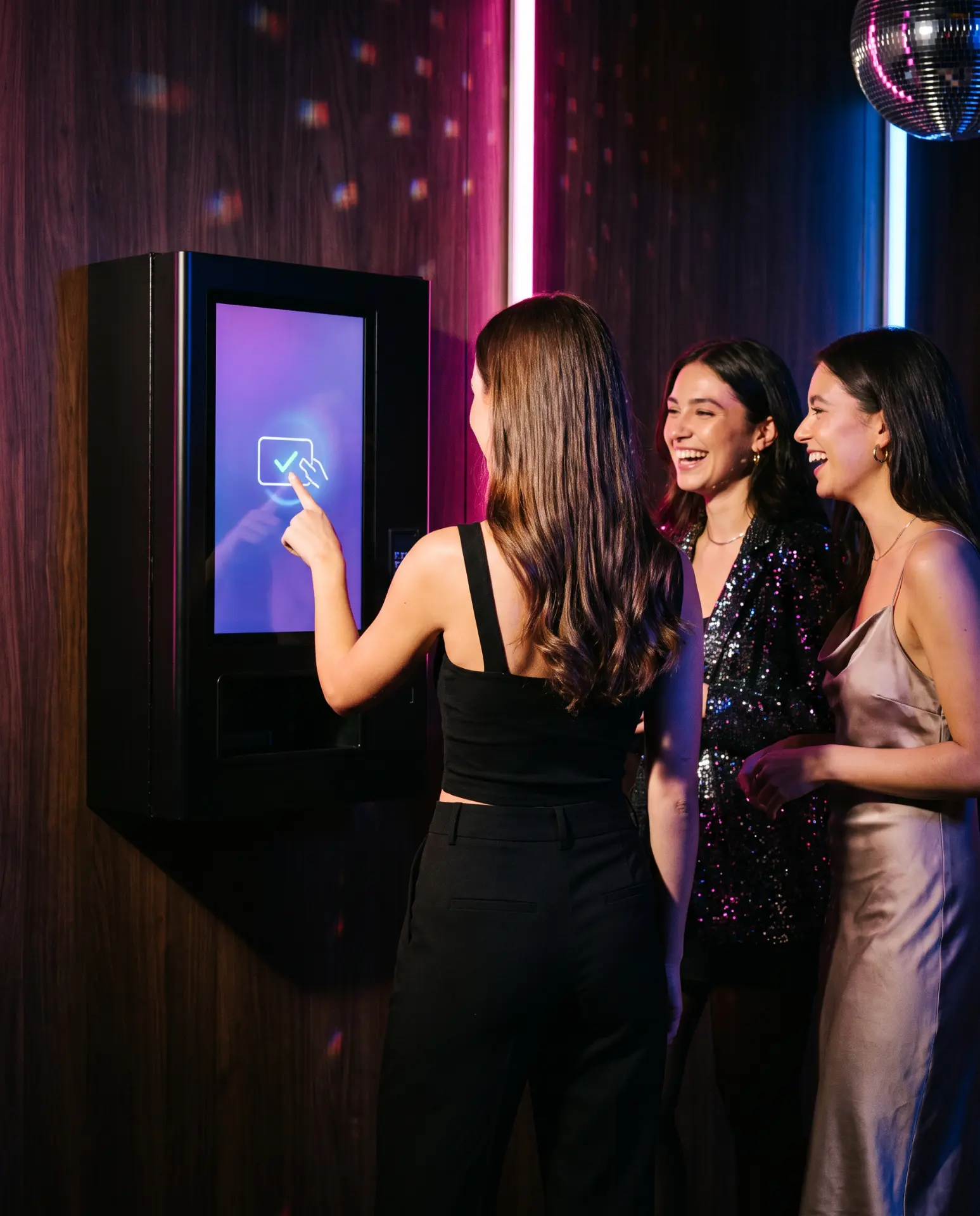 Tres chicas riendo junto a una máquina expendedora NoSpike en una discoteca
